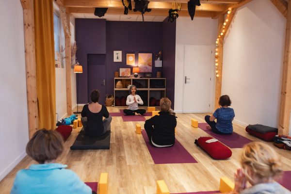 Séance de yoga pour adultes de 50 ans et plus à Annecy, pratiquant·e·s assis·es sur leurs tapis dans un studio lumineux.